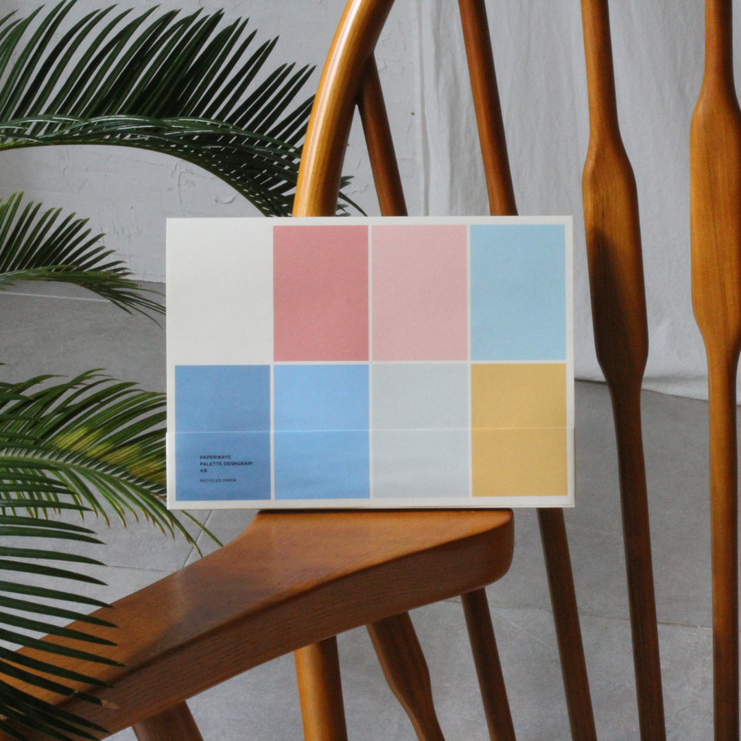 Color notepad on a wooden chair with a plant in the background