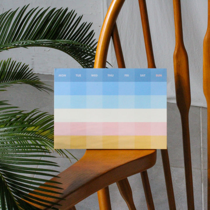 Monthly planner on a wooden chair with a plant in the background