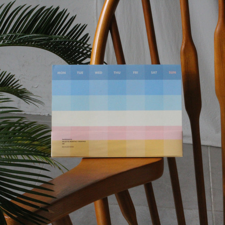 Monthly planner on a wooden chair with plants and a white wall in the background