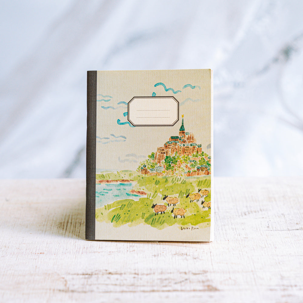 Notebook with a colorful illustration of a village on a hillside against a white background