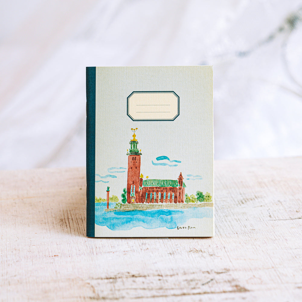 Notebook with a watercolor illustration of a building on a white surface