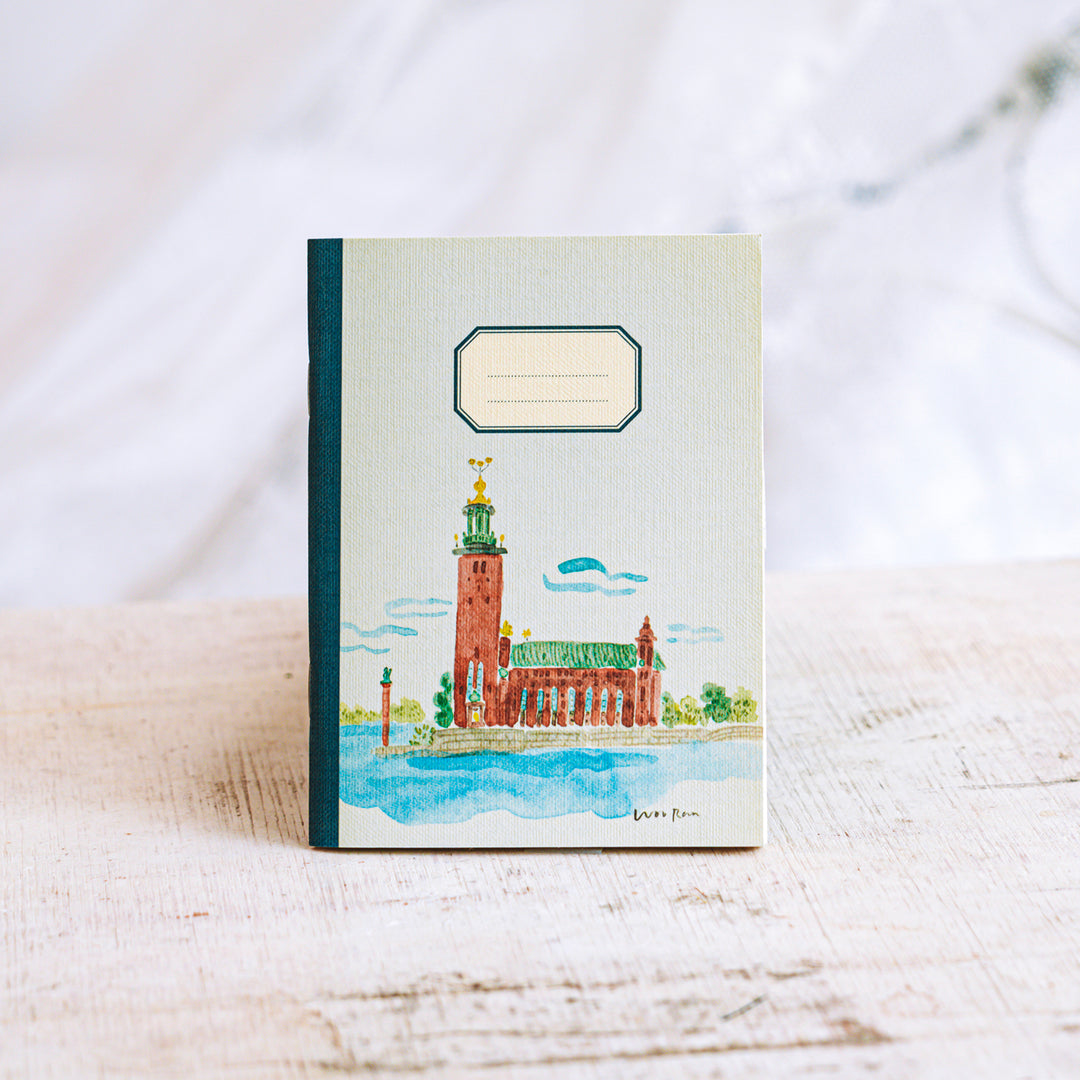 Notebook with a watercolor illustration of a building on a white surface