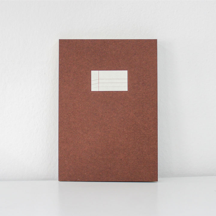 Brown textured notebook with a white label on a light gray background