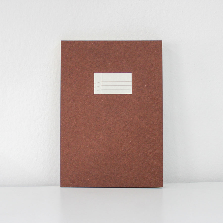 Brown textured notebook with a white label on a light gray background