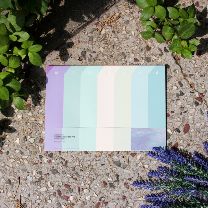 weekly deskpad on a textured surface with plants around